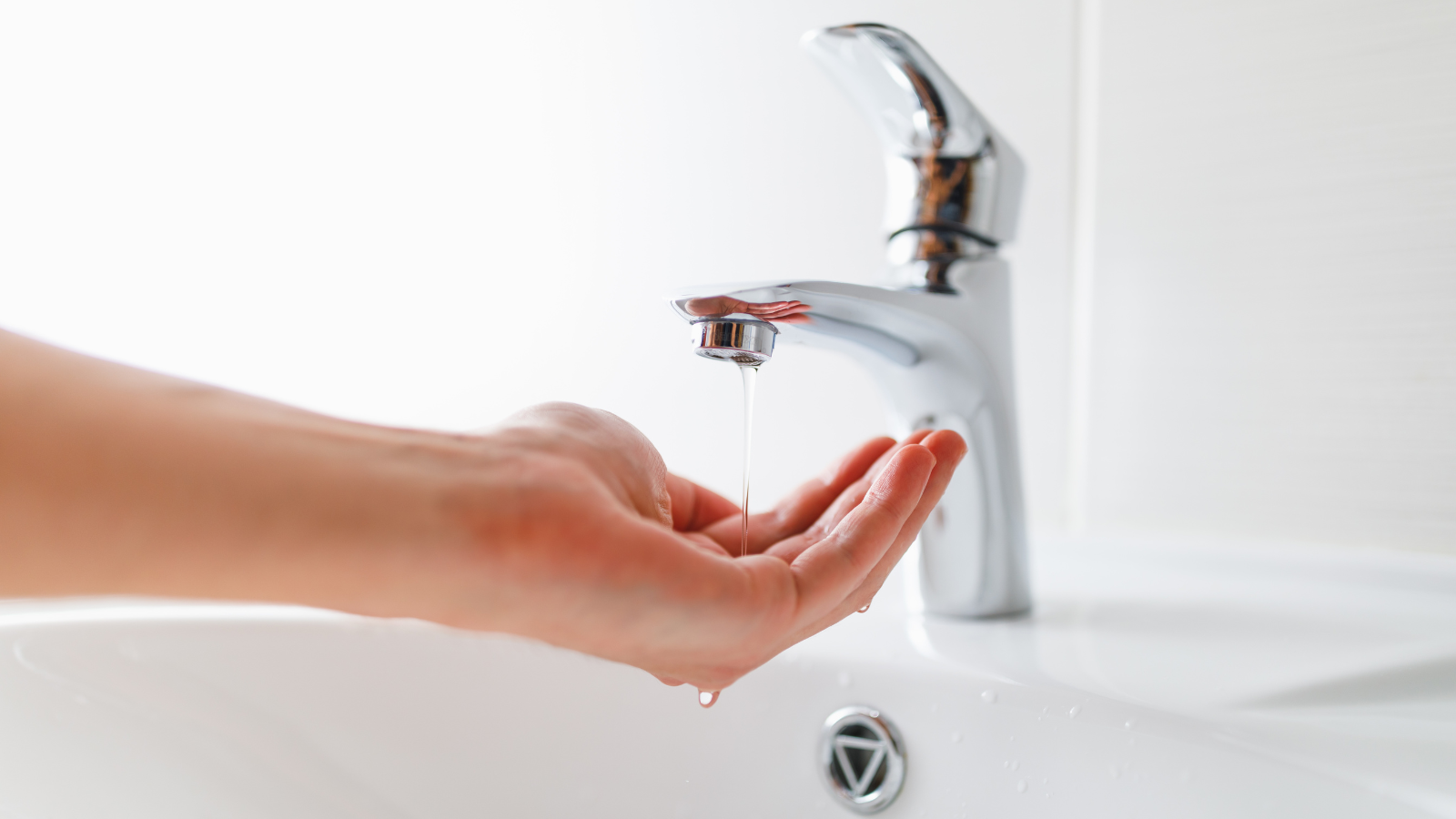 Hand cupping water under sink faucet with very low water pressure.