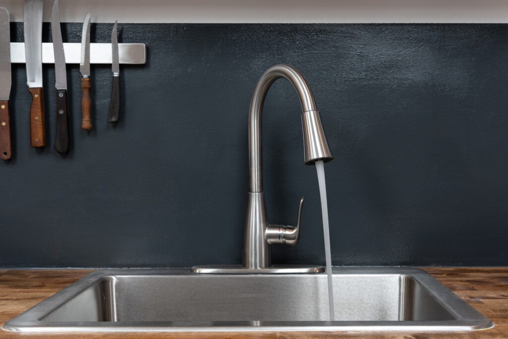Modern style brushed nickel kitchen sink with running water.